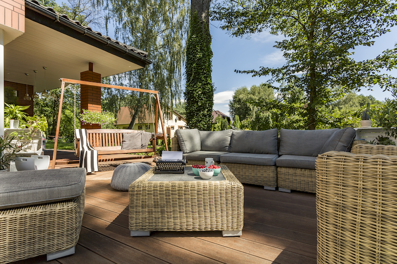 Buy a home. Cozy terrace in backyard with wicker furniture.