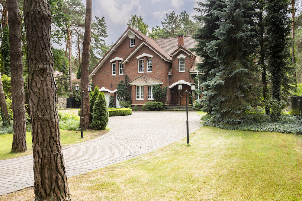 Buy a new home. Large, rural estate with brick facade and green lawn standing in the forest among trees